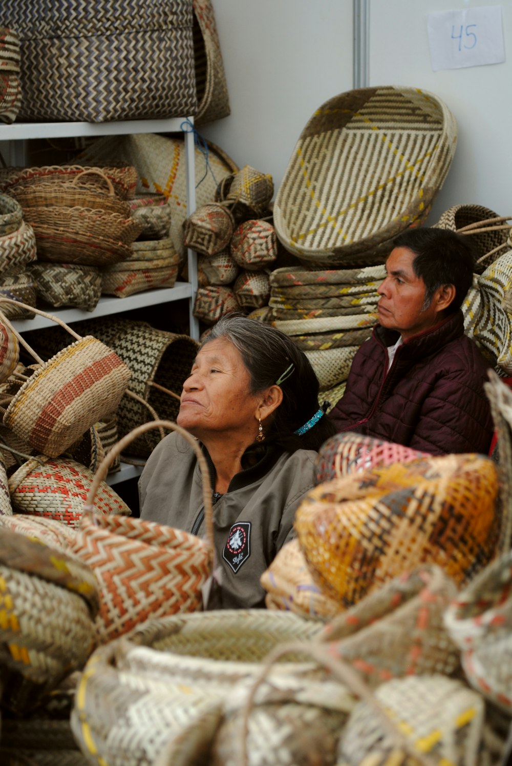 man and woman sitting on brown woven basket