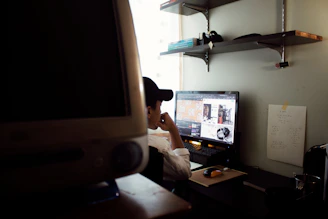 Dr. Kenneth Sessions thoughtfully working at his desk surrounded by technology and certification plaques.