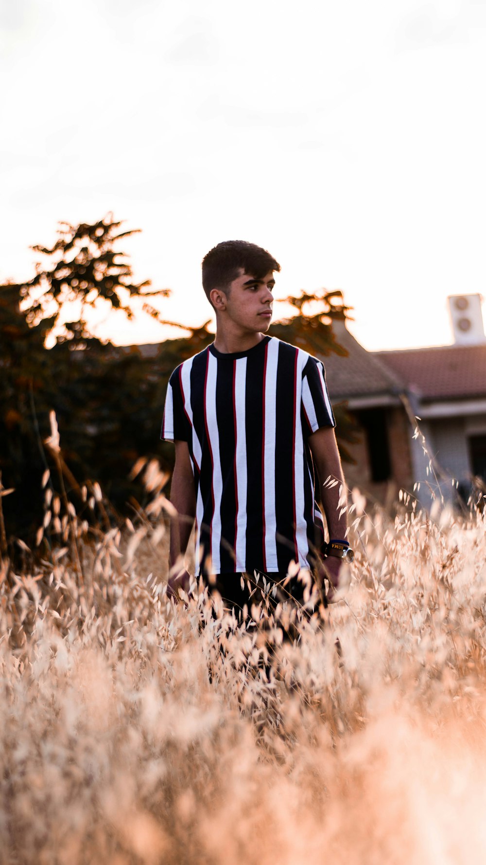 man in black and white striped shirt standing on brown grass field during daytime