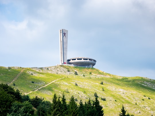 white and blue airplane on green grass field under white cloudy sky during daytime in Buzludzha Monument Bulgaria