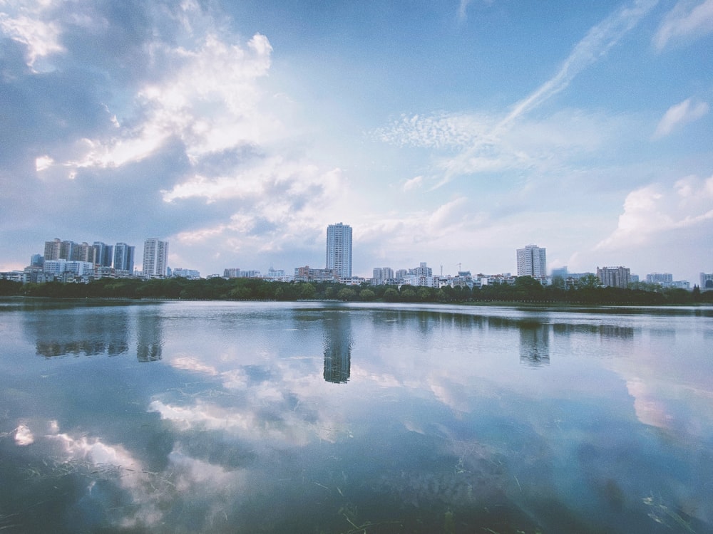 city skyline across body of water under blue and white sunny cloudy sky during daytime