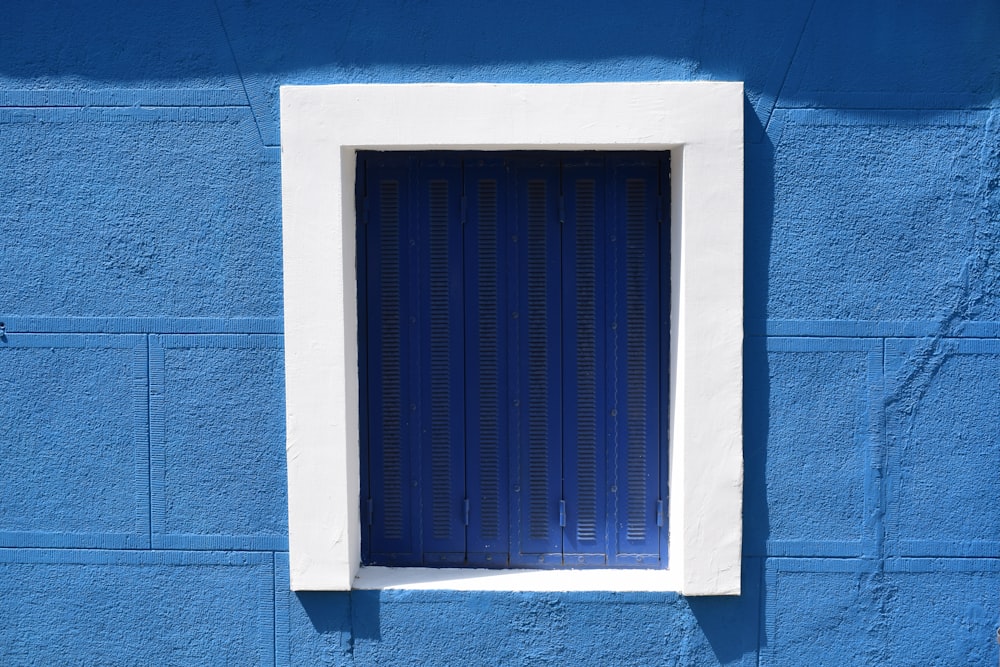 janela azul emoldurada de madeira branca