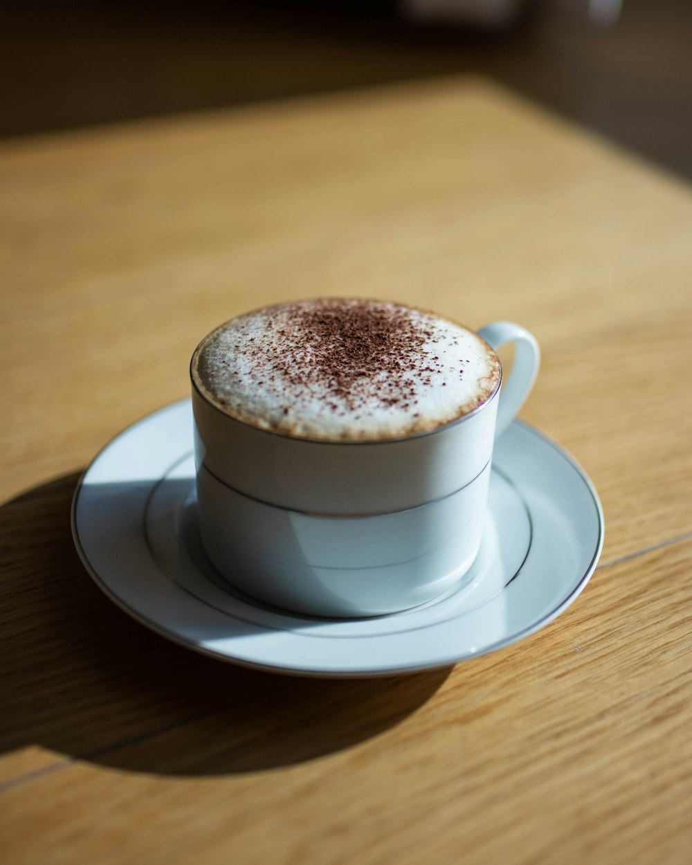 white ceramic cup with saucer on brown wooden table