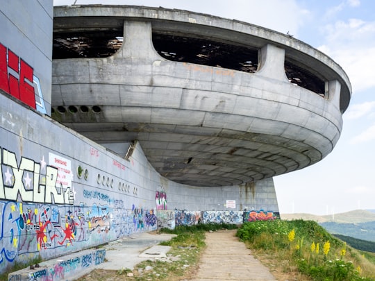 white concrete building near green trees during daytime in Buzludzha Bulgaria