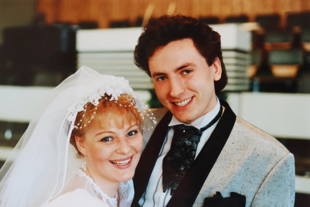 man in black suit beside woman in white floral wedding dress