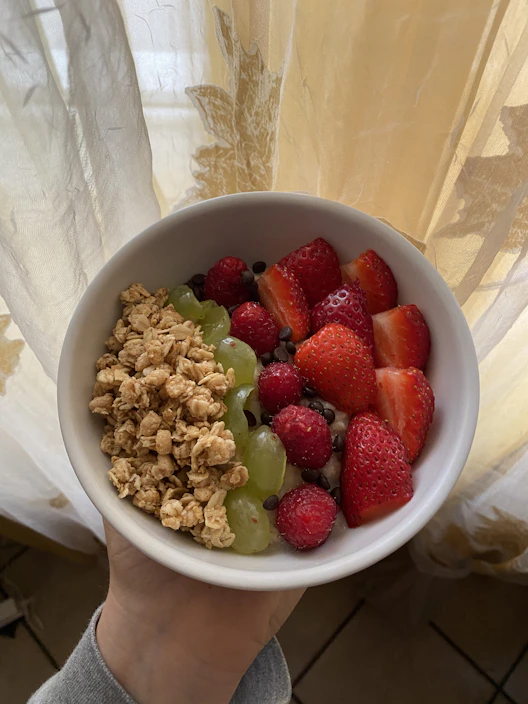 A vibrant bowl of mixed fresh fruits and granola with morning sunlight streaming in