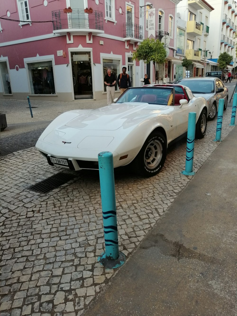 white and black porsche 911 parked on sidewalk during daytime