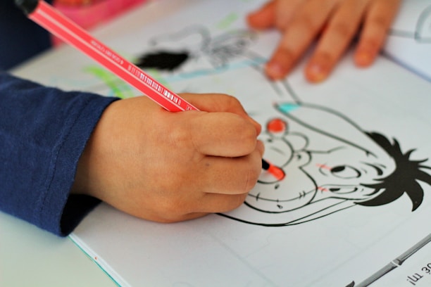 person holding red pencil on white printer paper