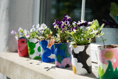 A set of hand-painted ceramic planters with soft floral patterns on a windowsill.