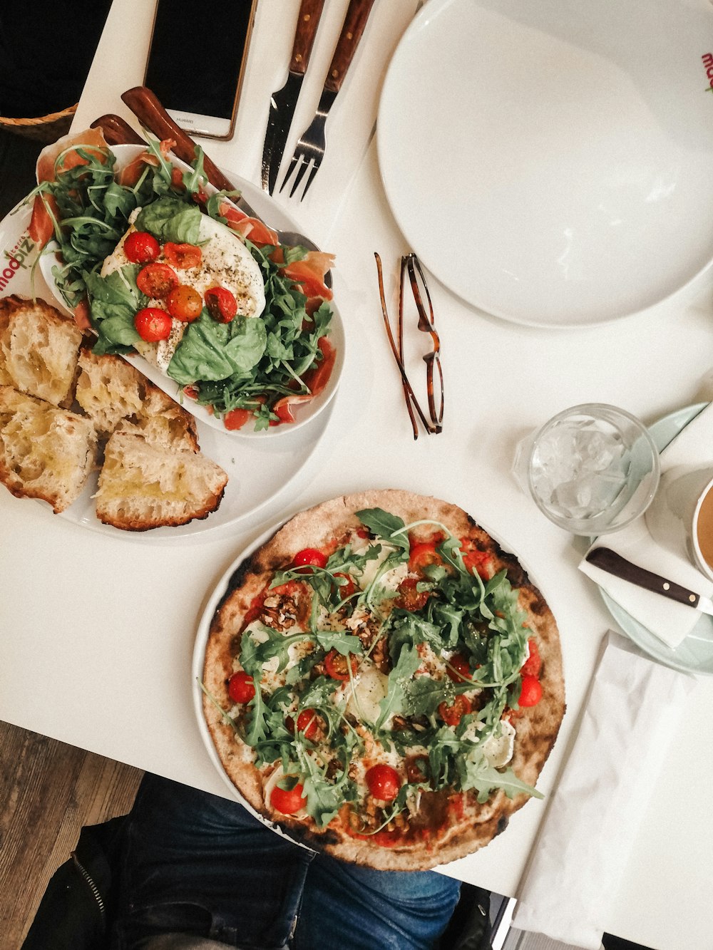 pizza with tomato and green vegetable on white ceramic plate