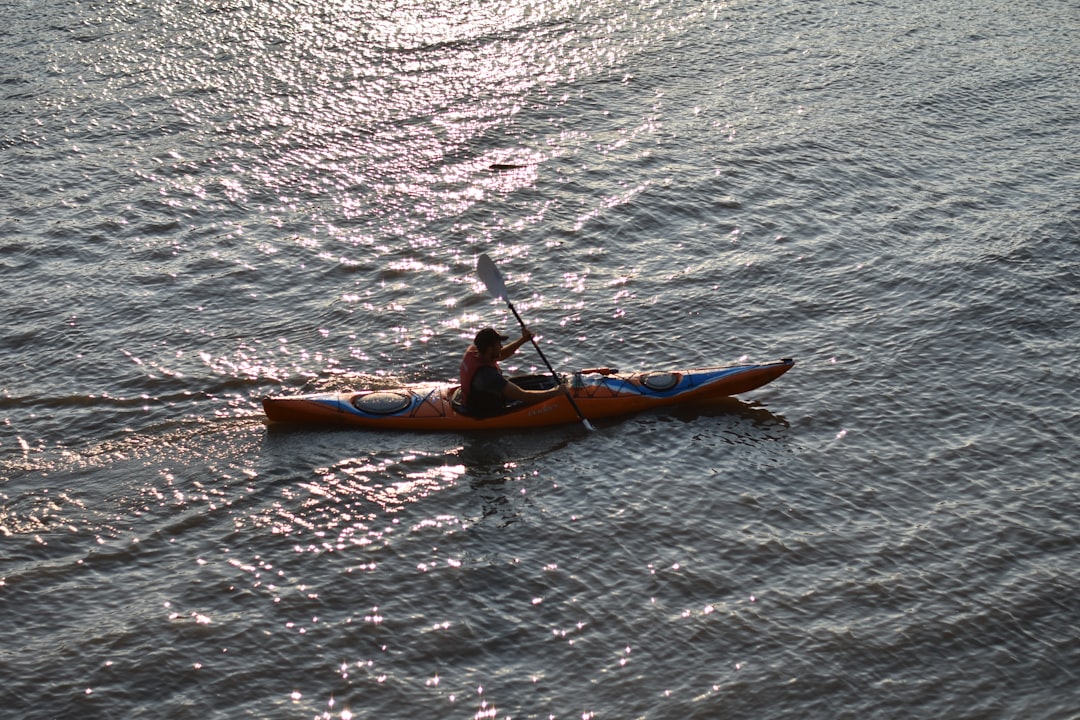 man in orange kayak on body of water during daytime