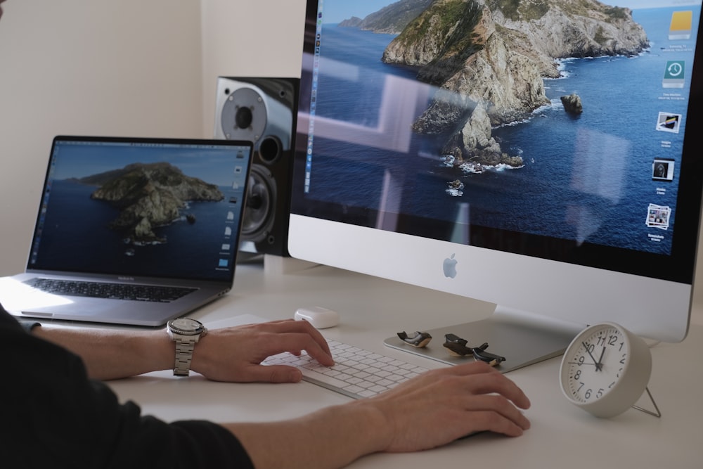 person using silver imac and apple keyboard