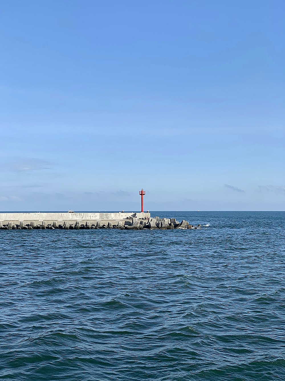 red and white lighthouse on the sea during daytime