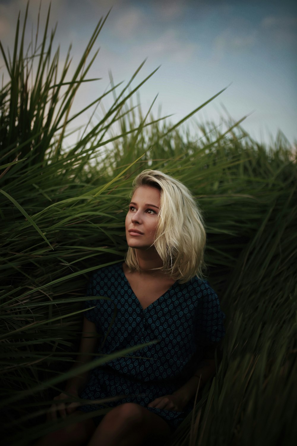 woman in blue and white checkered dress shirt standing near green plants during daytime