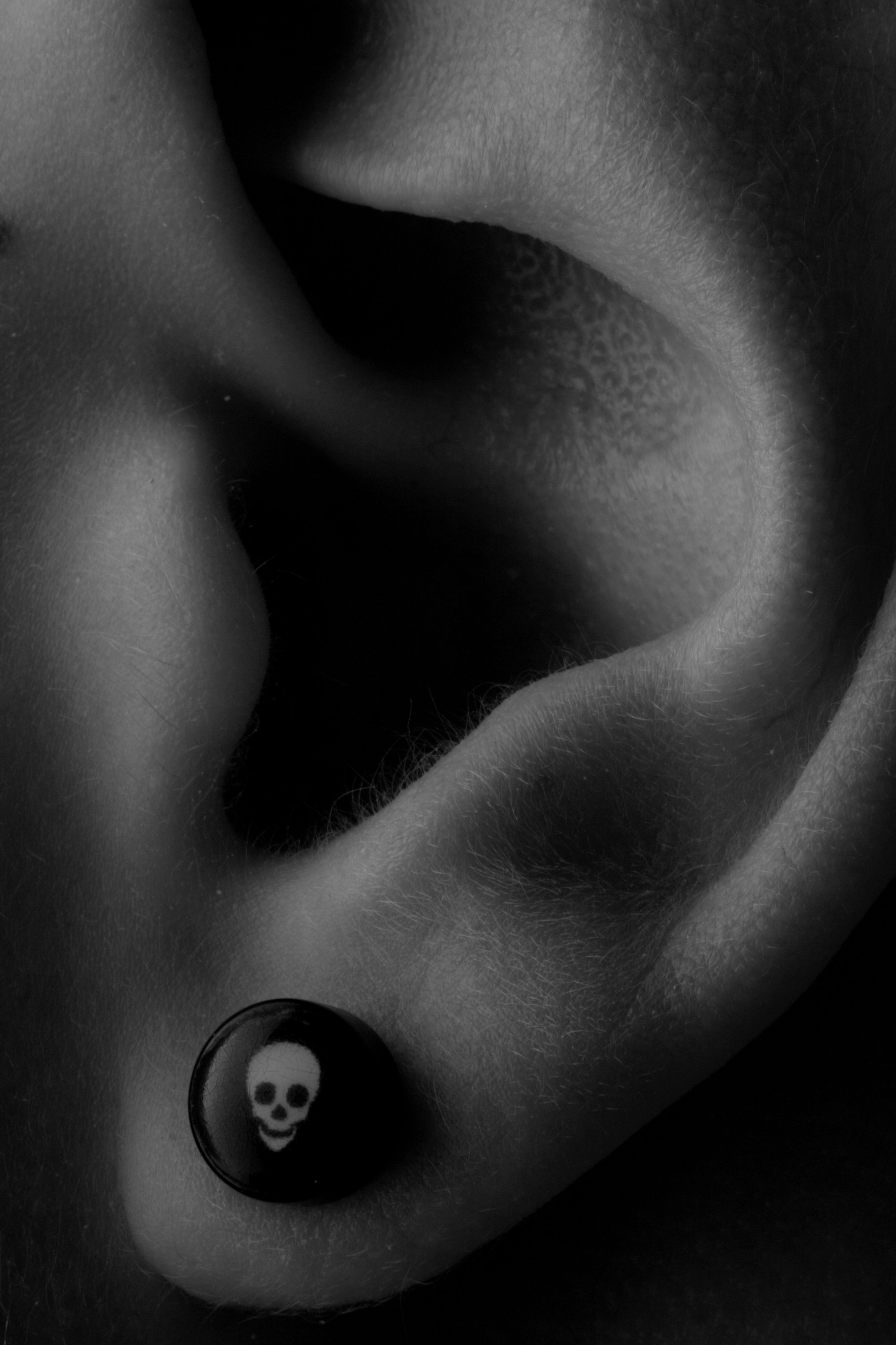 Detail shot of ear with skull earring