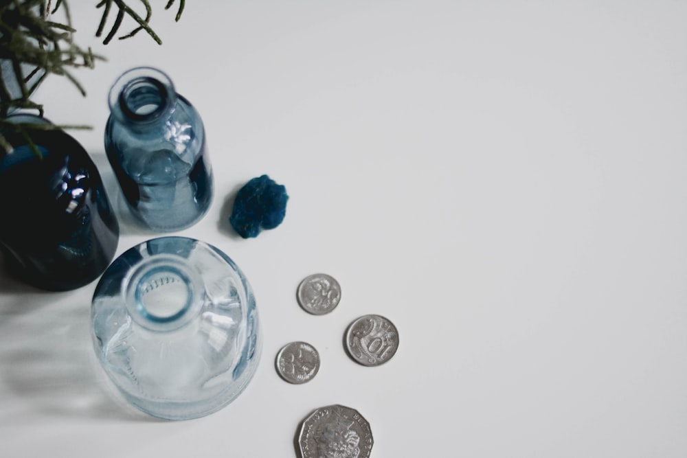 silver round coins beside blue glass bottle