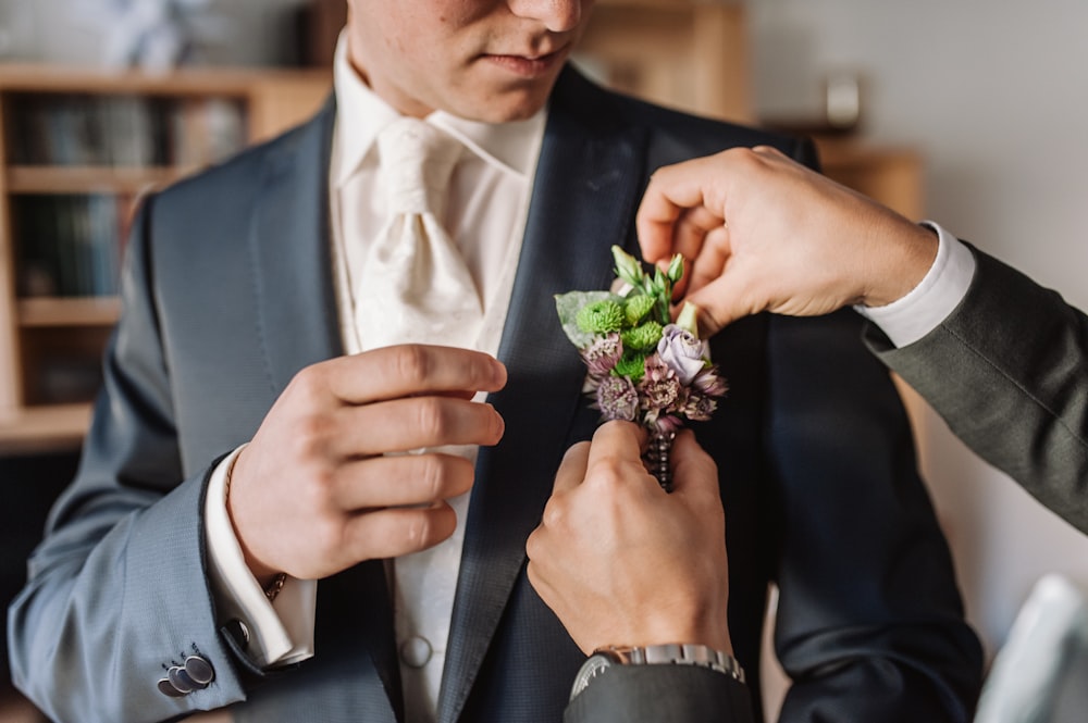 man in black suit holding bouquet of flowers