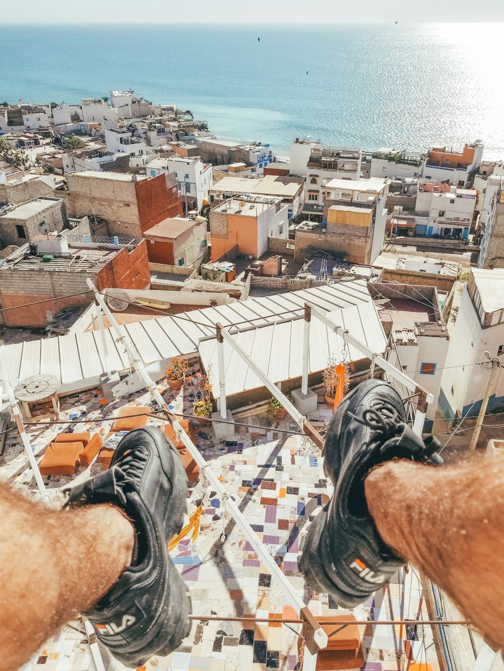 person in black and white sneakers sitting on brown concrete building during daytime