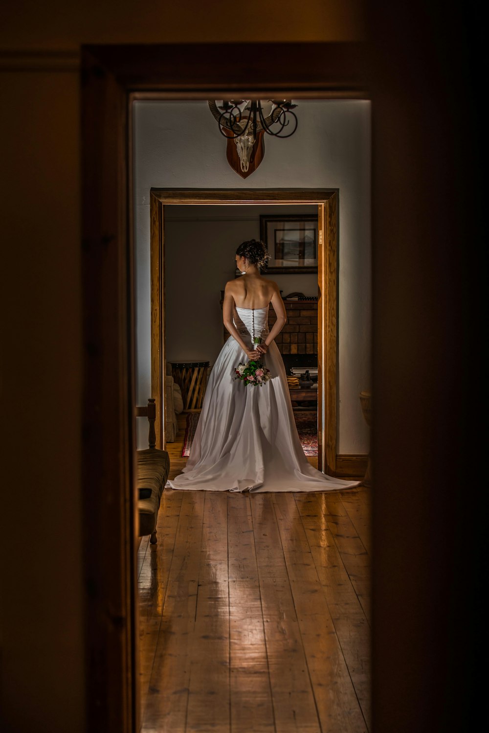 Femme en robe de mariée blanche debout sur un plancher en bois brun