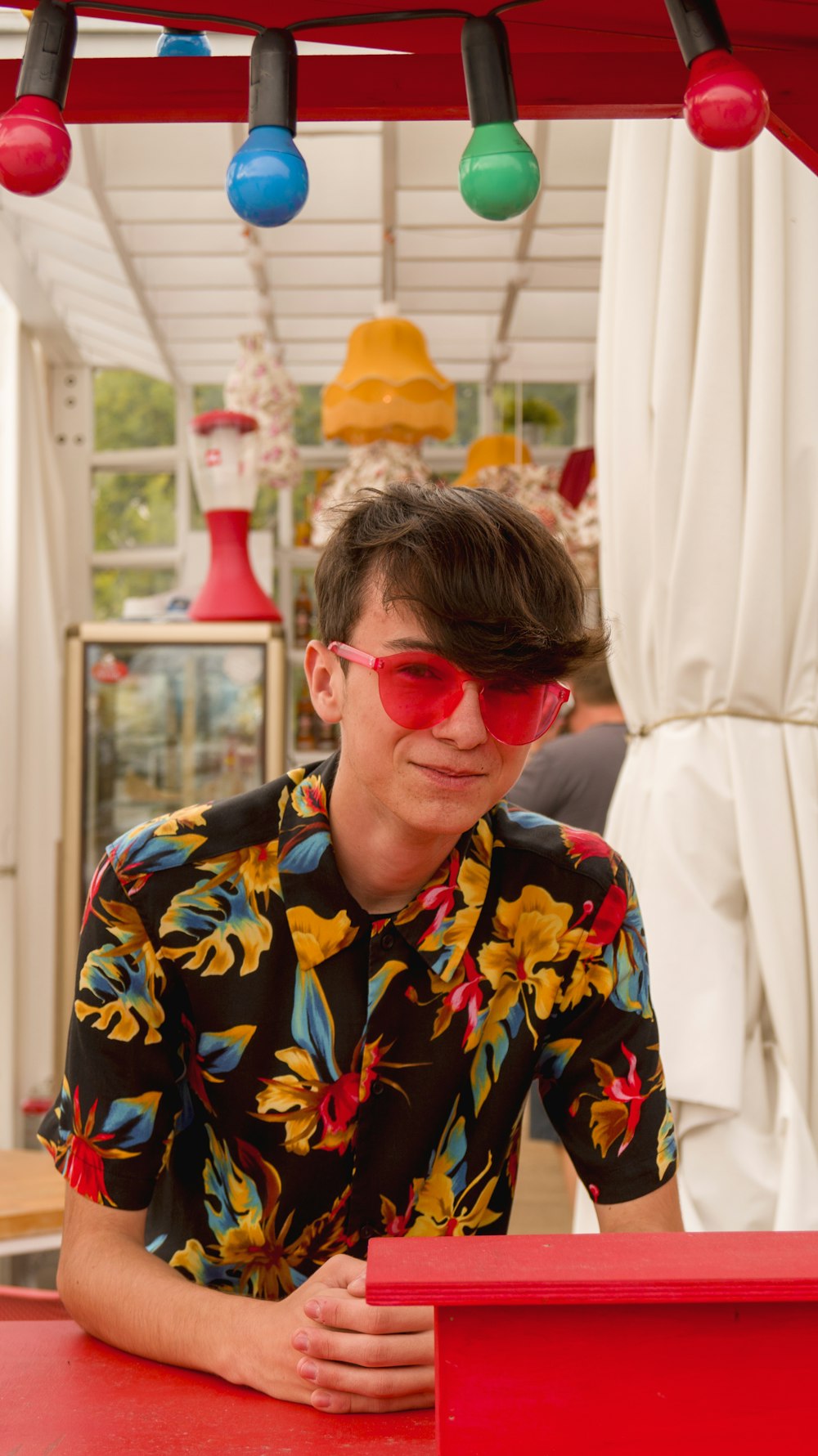 woman in yellow black and red floral button up shirt wearing red sunglasses