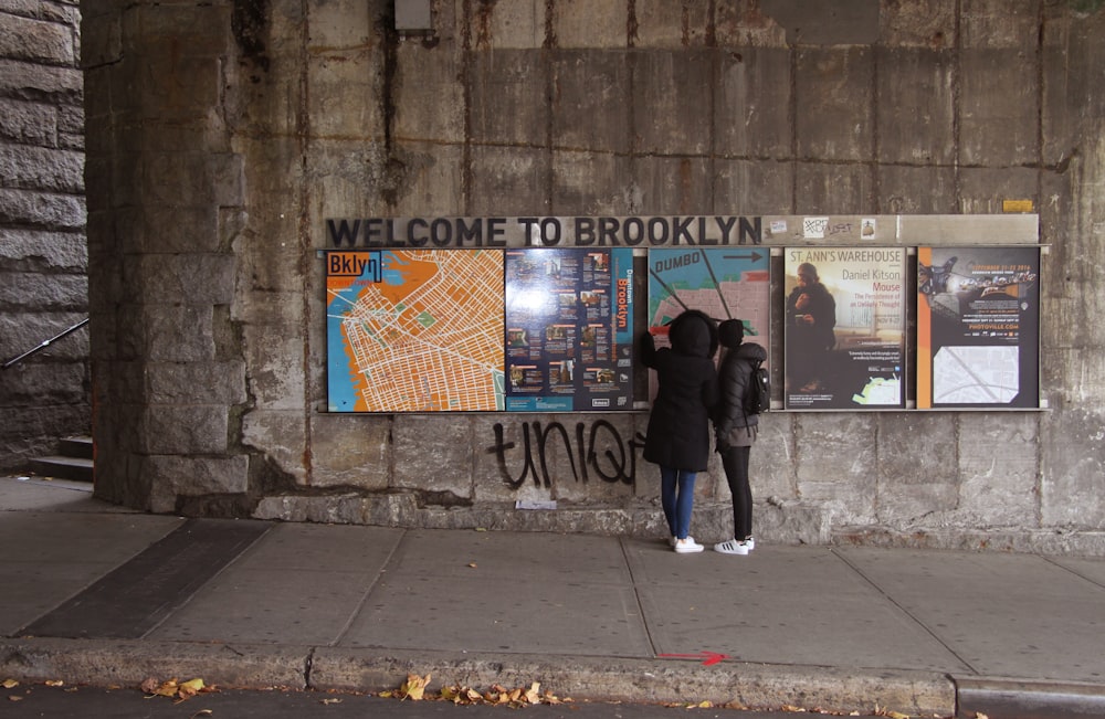 a couple of people standing next to a wall