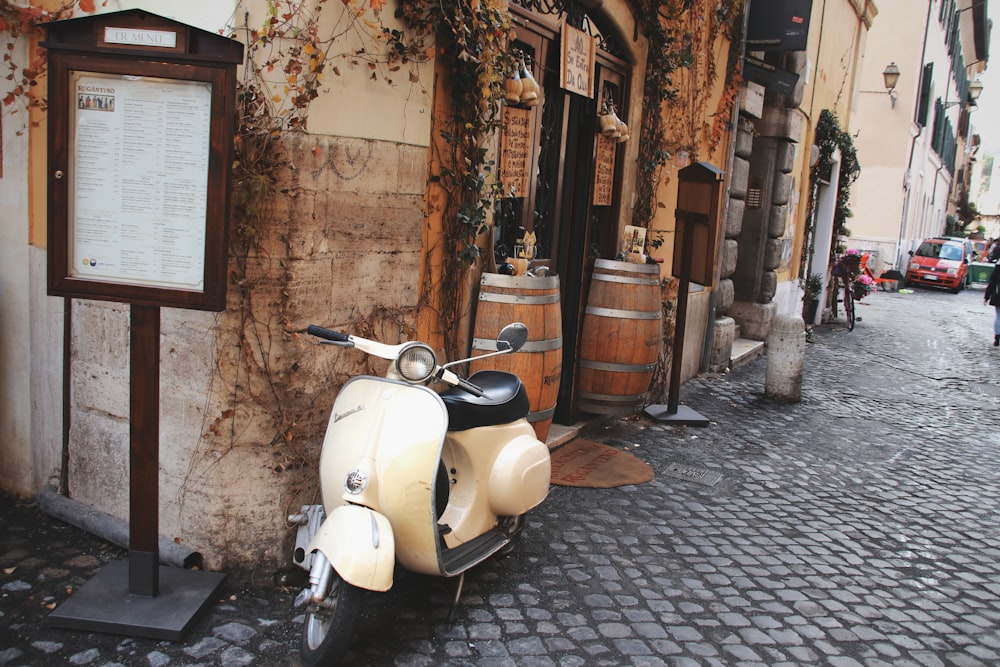 white motor scooter parked beside brown wooden door