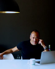 A thoughtful man reviewing career plans on a digital tablet.