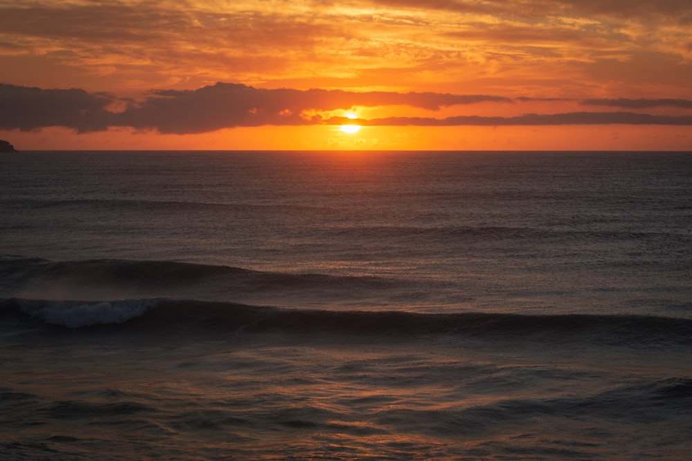 Olas del océano rompiendo en la costa durante la puesta de sol