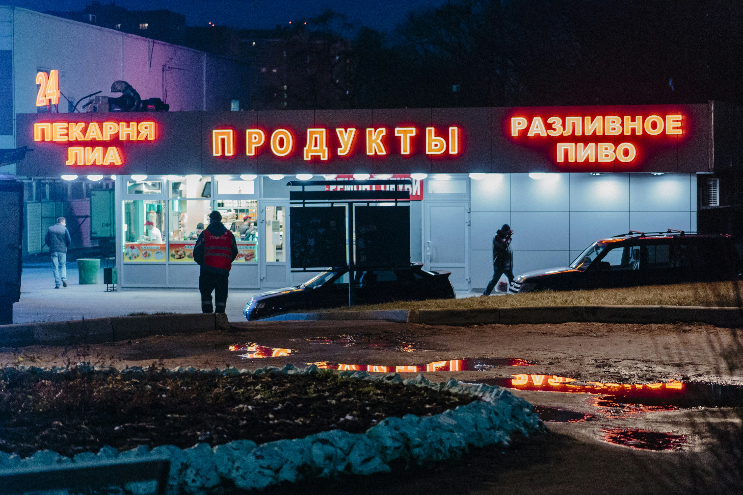 man in black jacket and black pants standing near red and white UNKs store during