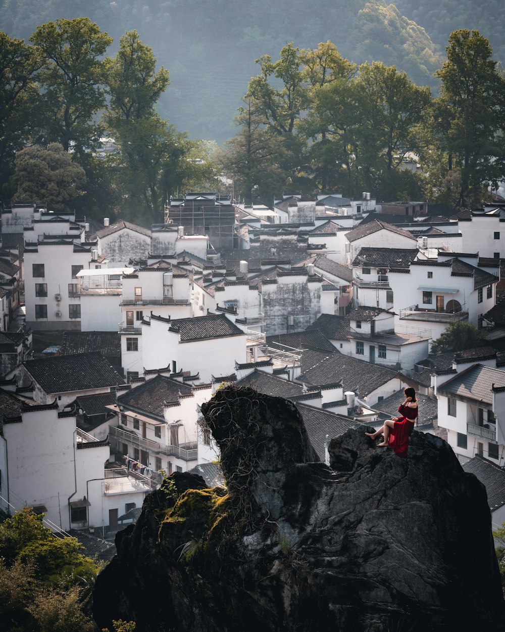 person in red jacket standing on rock near body of water during daytime