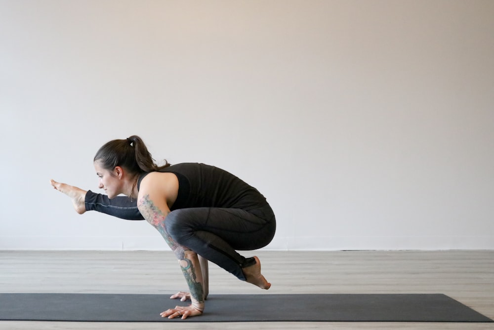 woman in black tank top and blue denim jeans sitting on gray concrete floor