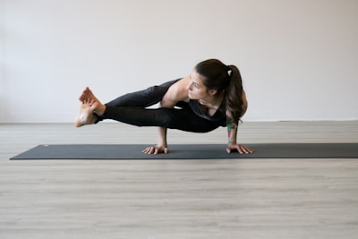 A minimalist yoga pose captured in silhouette against a pale, spacious wall.