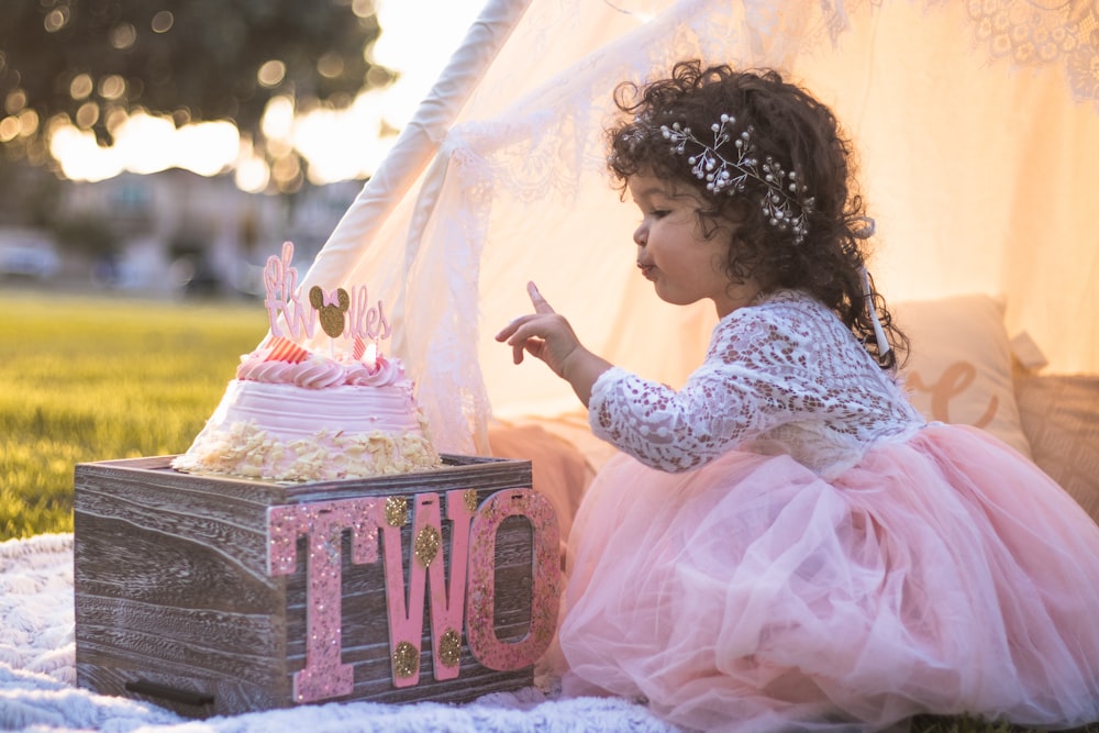 girl in gray and white floral dress sitting on pink and white floral box