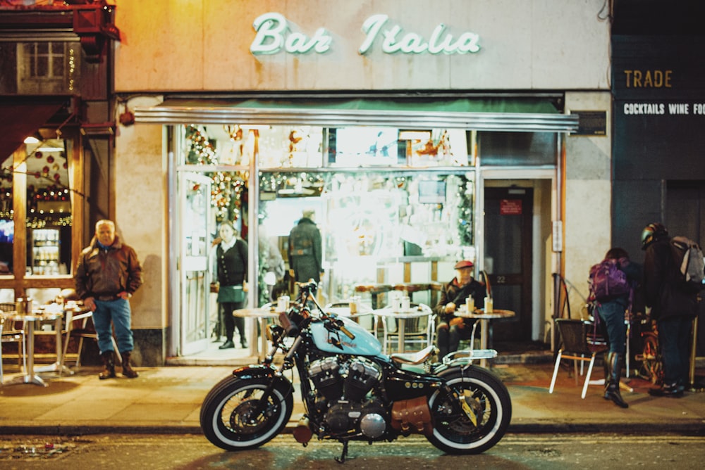 man in black jacket standing beside black motorcycle