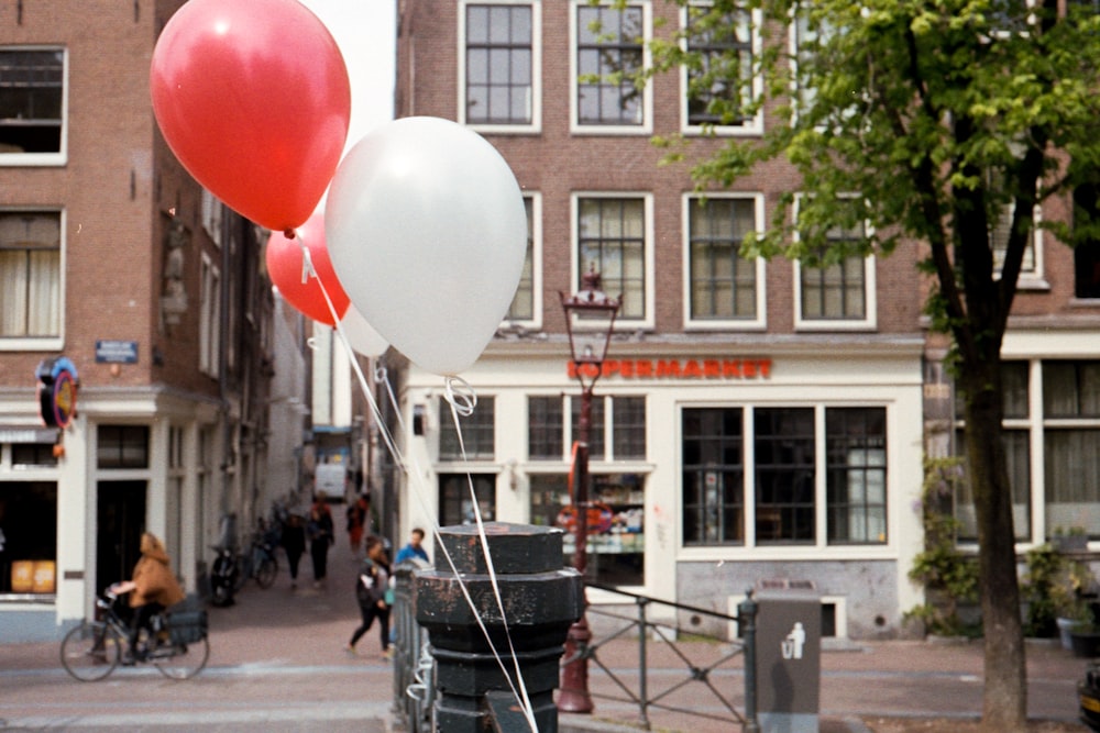 people walking on sidewalk with balloons on the street during daytime