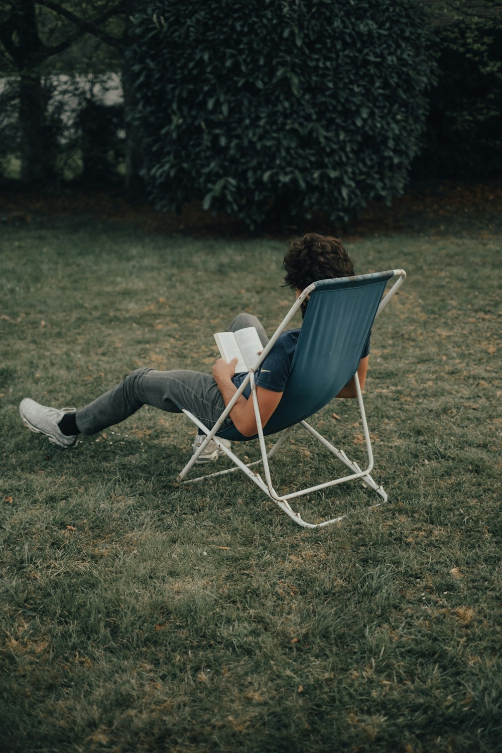 woman in black shirt and black pants sitting on blue and white folding chair