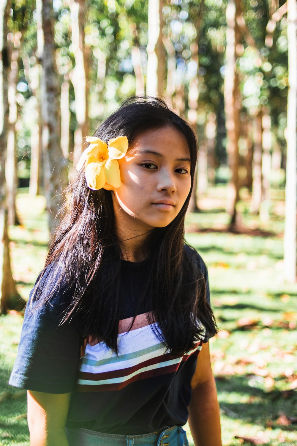 woman in gray and white shirt with yellow flower on ear