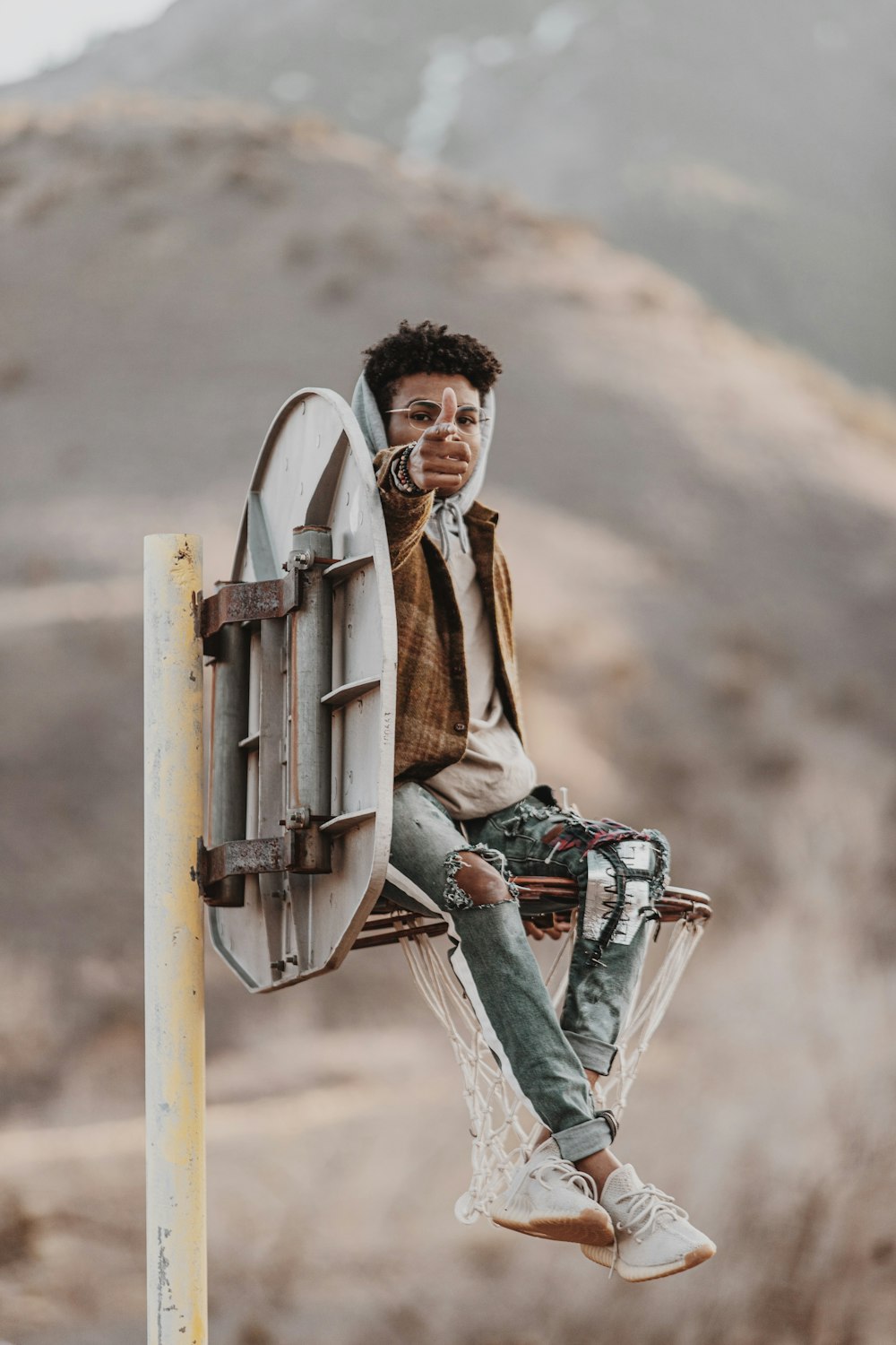 man in brown coat and blue denim jeans sitting on brown wooden ladder during daytime