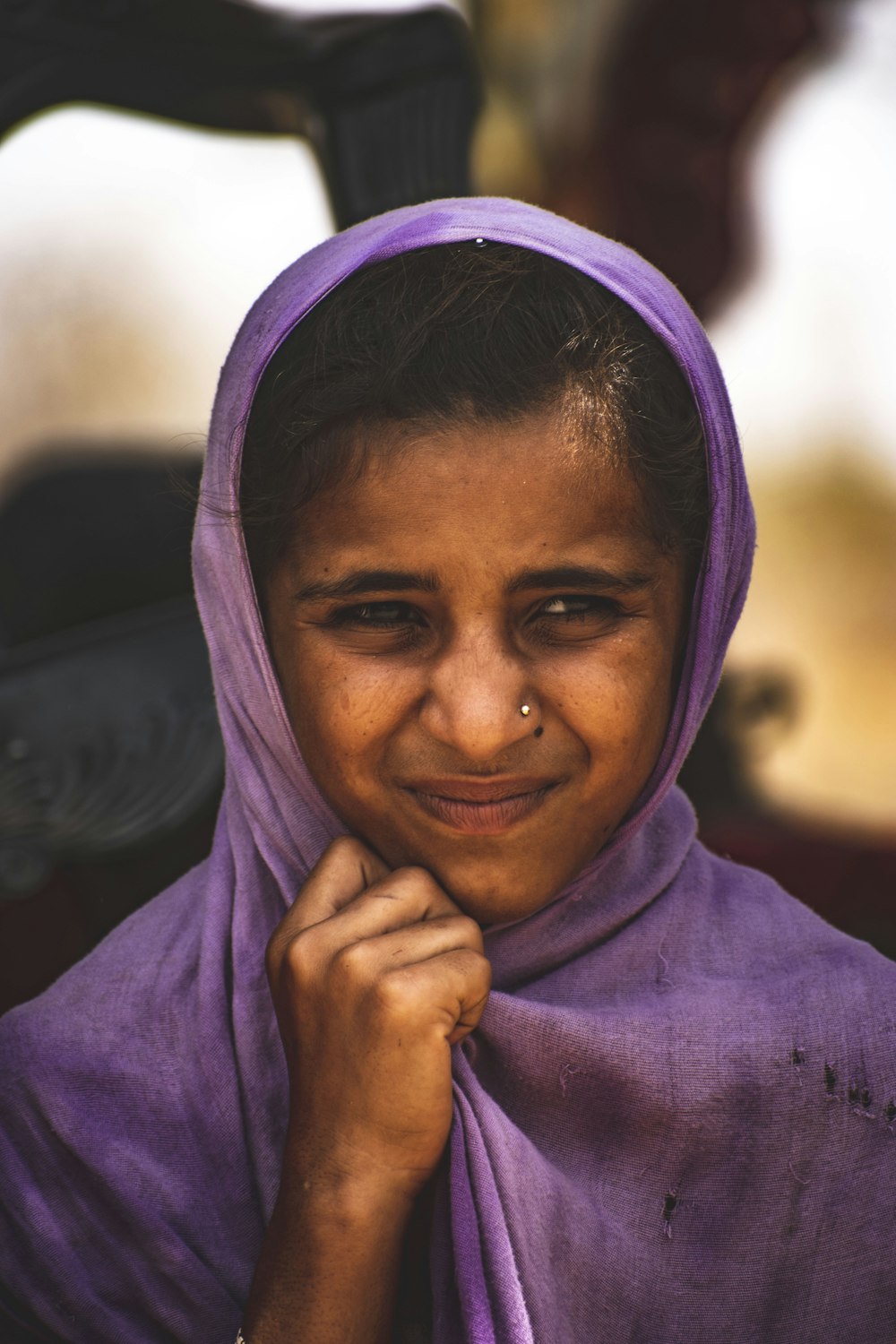 a young girl wearing a purple shawl smiles at the camera