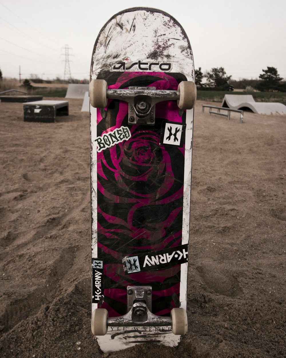 white black and red skateboard on brown sand during daytime