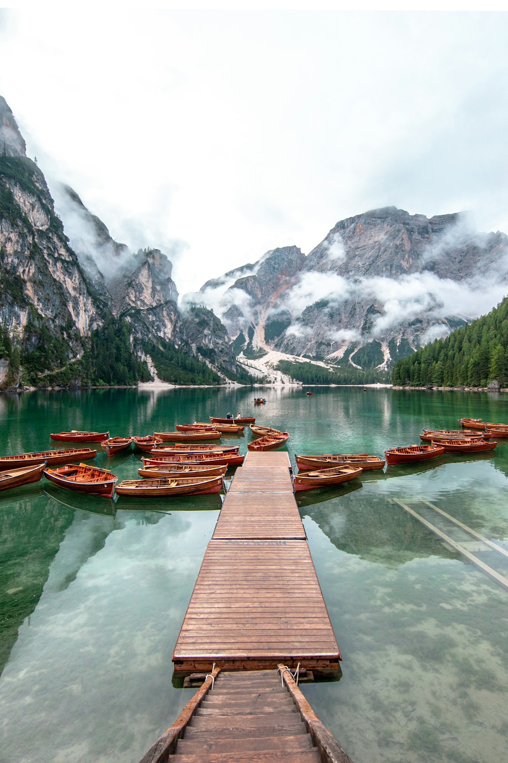 昼間の山の近くの湖に浮かぶ茶色の木造船着き場