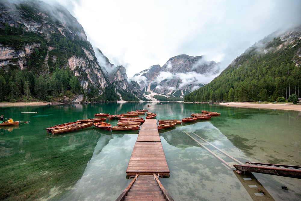 a wooden dock in the middle of a lake surrounded by mountains