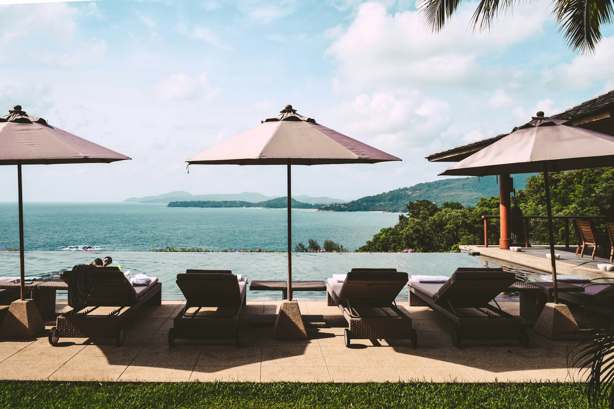 View of the Andaman Sea in Phuket, Thailand. Lounge chairs by the pool.