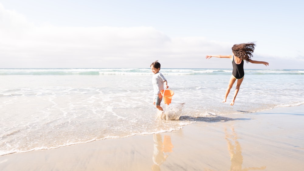 2 boys running on beach during daytime