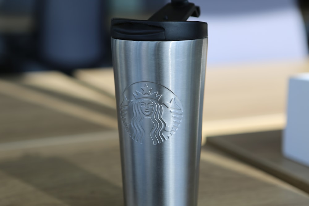 Mug de voyage Starbucks argenté sur table en bois marron