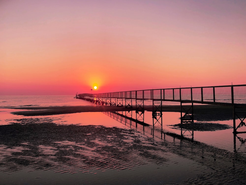 silhouette of dock on sea during sunset