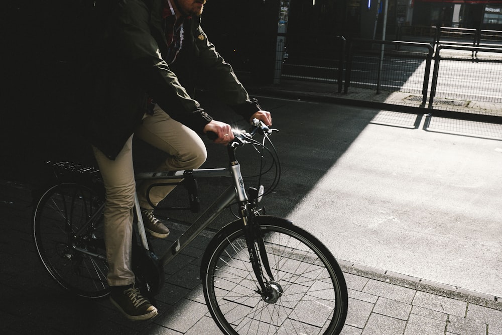 man in black jacket and brown pants riding on black bicycle