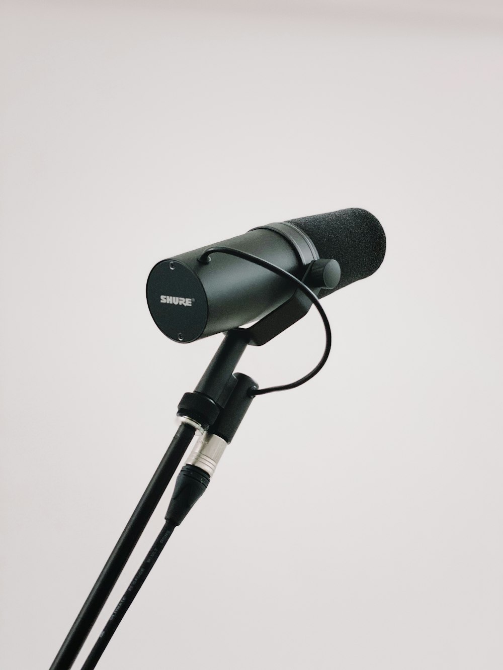 Micrófono negro con soporte sobre fondo blanco