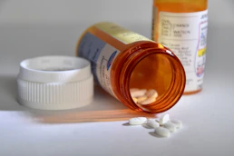 Prescription bottle with tablets spilled beside additional medication containers.