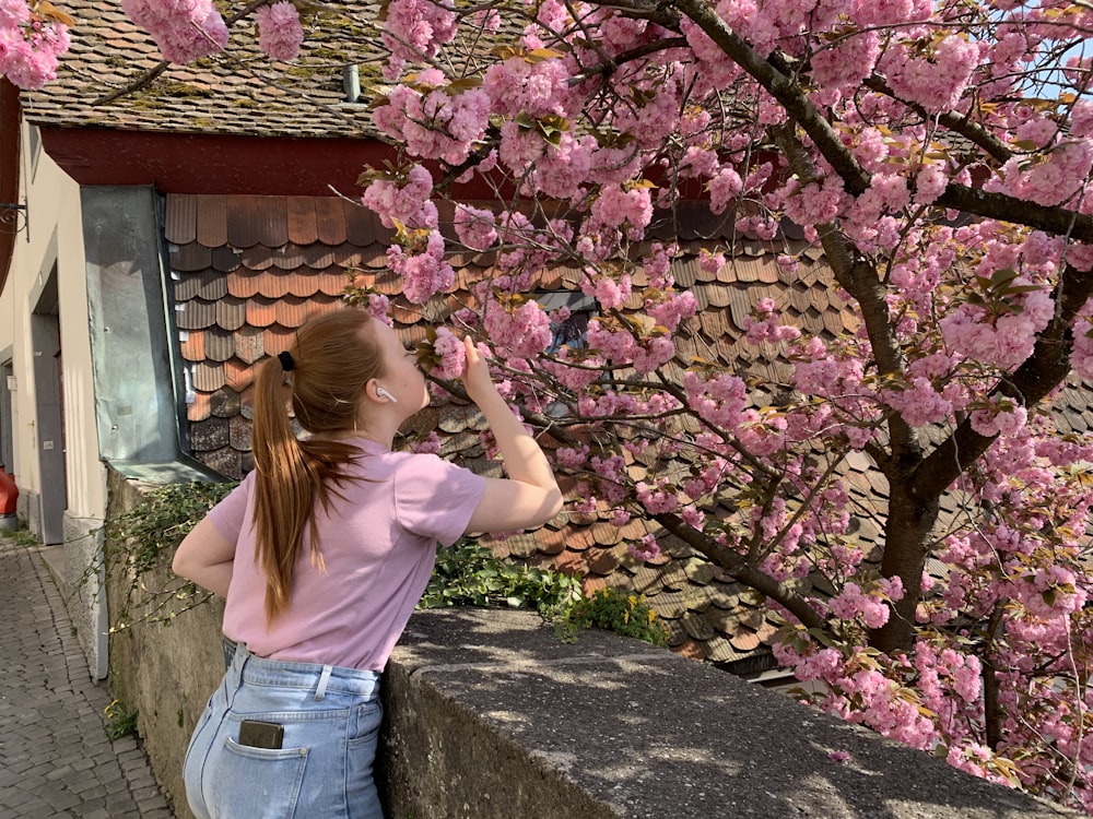 a woman taking a picture of a flowering tree